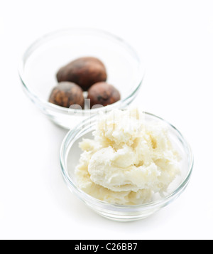 Shea butter and nuts in glass bowls isolated on white Stock Photo