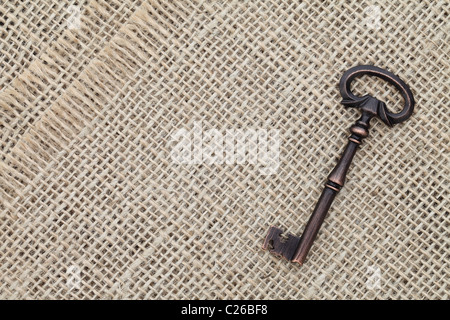Old key isolated on burlap background Stock Photo