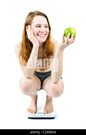 Healthy happy young woman holding apple on bathroom scale isolated on white Stock Photo