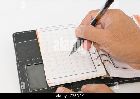 Hands holding a pen while marking the calender Stock Photo