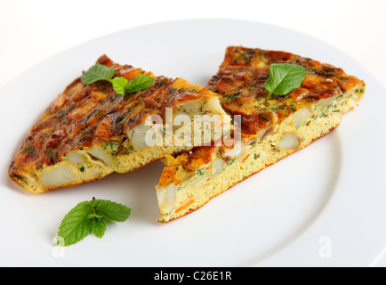 Slices of Spanish omelet or tortilla de patatas on a white plate, garnished with mint leaves Stock Photo