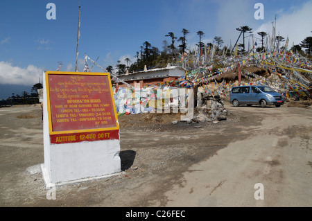 Sign and prayer flags at Thrumshingla Pass, the border between central and eastern Bhutan Stock Photo