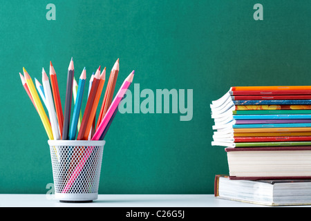 Image of crayons and exercise books against blackboard Stock Photo