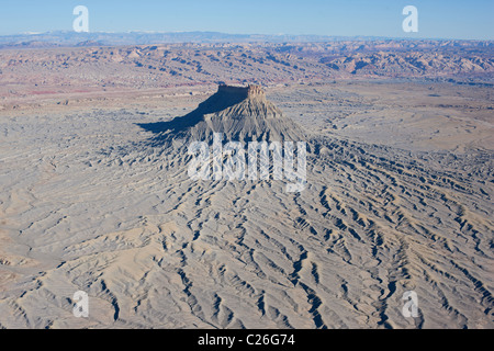 AERIAL VIEW. Butte emerging (by about 500 meters) out of the relatively flat surrounding desert. Factory Butte. Caineville, Wayne County, Utah, USA. Stock Photo