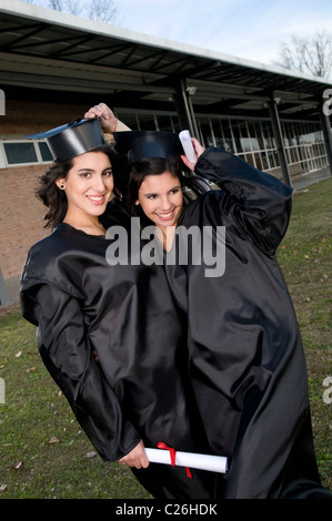 Two, students, schoolmates, women, woman, looking, look, at, the, camera, smile, smiling, celebrate, celebrating, diploma. Stock Photo