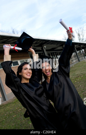 Two, students, schoolmates, smile, smiling, celebrate, celebrating, student, in, line, stand, up, holding, hold, the, a, diploma Stock Photo
