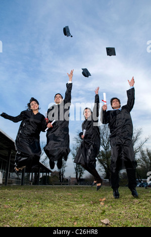 Four, students, schoolmates, jump, jumping, celebrate, celebrating, end, of, the, course,  smiling, looking, at, the, camera. Stock Photo