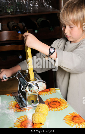 Stock photo of a young boy making fresh pasta with a pasta machine. Stock Photo