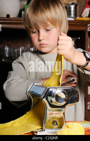 Stock photo of a young boy making fresh pasta with a pasta machine. Stock Photo