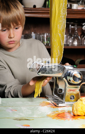 Stock photo of a young boy making fresh pasta with a pasta machine. Stock Photo