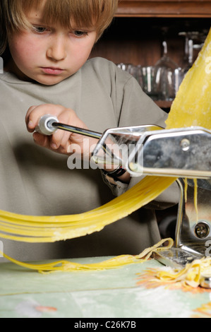 Stock photo of a young boy making fresh pasta with a pasta machine. Stock Photo