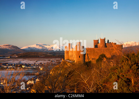 Harlech Castle in winter with Snowdon and Snowdonia mountain range in snow Gwynedd North Wales UK Stock Photo
