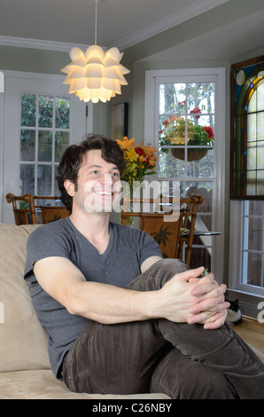 casually dressed man relaxing on couch. Stock Photo
