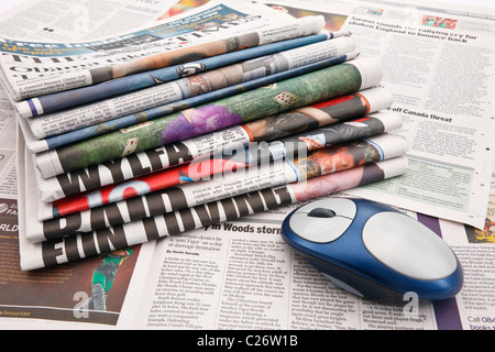 Pile of newspapers with a computer mouse to represent the concept of changing future of the press on the Internet. England UK Britain Stock Photo