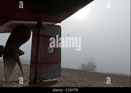 A fishing boat landing on the shingle beach on Hastings Stade East Sussex UK on a foggy day Stock Photo