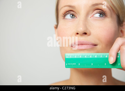 Woman Holding Measuring Ruler under Mouth