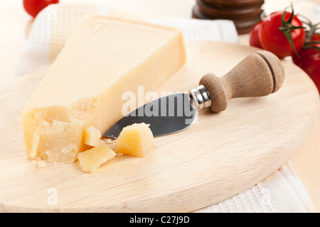 parmesan cheese and knife on wooden platter Stock Photo