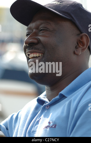 A side-profile view of middle-aged black man wearing a baseball cap, laughing. Stock Photo