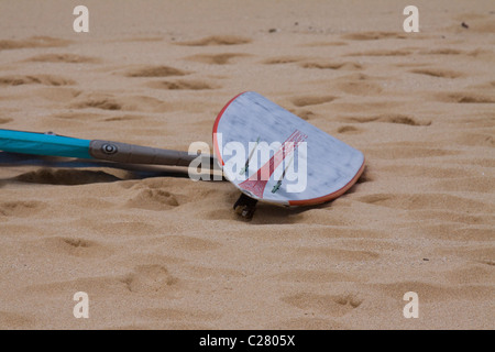 Windsurfer sits waiting on the golden sand on famous Hookipa Beach. Maui, Hawaii Stock Photo