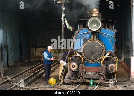 Engineers doing a service of a narrow-gauge old-style steam train before the route  and fill a tank with water. Stock Photo