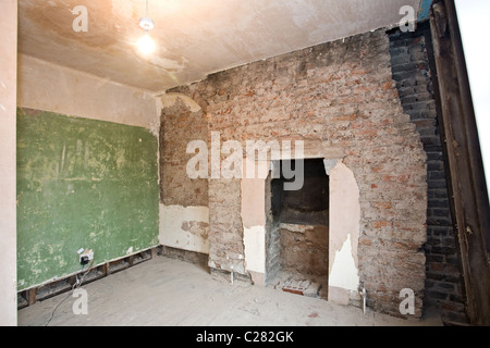 Plaster wall, brick wall and fireplace in room undergoing renovation. London, England, UK Stock Photo