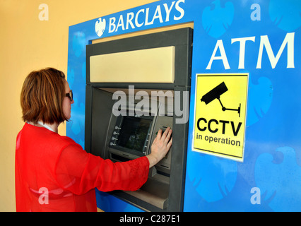 Barclays Bank branch and ATM. Woman using cashpoint. Stock Photo