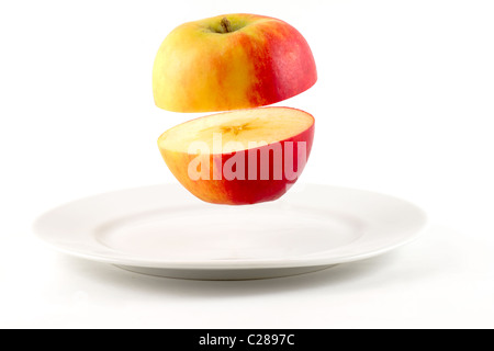 Sliced Apple hovering over white plate Stock Photo