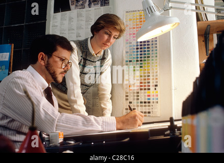 Male and female graphic designers working at a drafting table Stock Photo