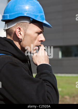 Profile of a serious manual worker in blue hard hat Stock Photo