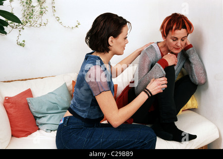 Stressed mother and teenage girl soothe mom at home on sofa.
