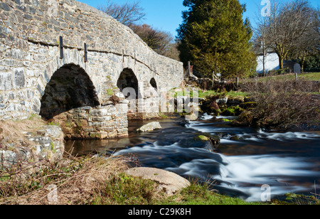 Granite built stone bridge at Postbridge on Dartmoor using slow shutter speed to blur flowing water, Devon Stock Photo