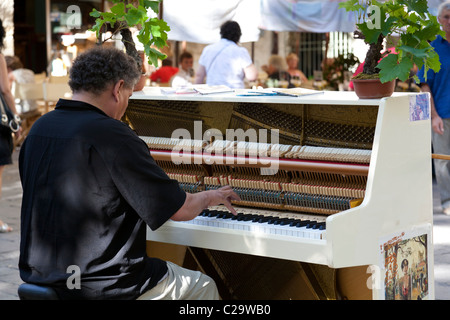 Pianist plays for the passing shoppers and tourists in the centre of Uzes, Gard, Languedoc-Roussillon, France. Stock Photo