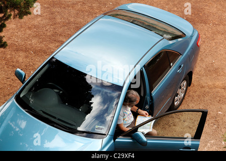Looking down to a man reading a road map in motor vehicle, Stock Photo