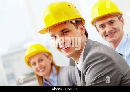 A smiling architect in helmet against his two colleagues Stock Photo