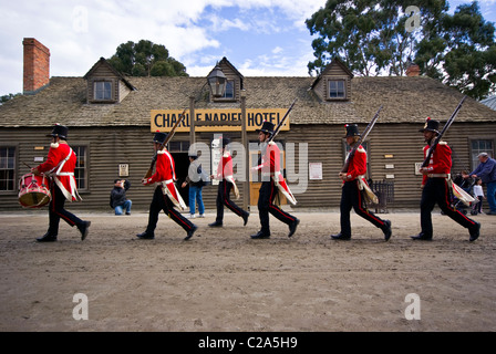 A patrol of British Redcoat soldiers march in formation past a hotel. Stock Photo