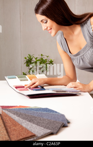 A female interior designer looking at rug samples from a catalogue Stock Photo