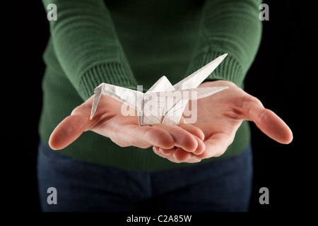 female hands holding an origami crane, focus on the bird Stock Photo