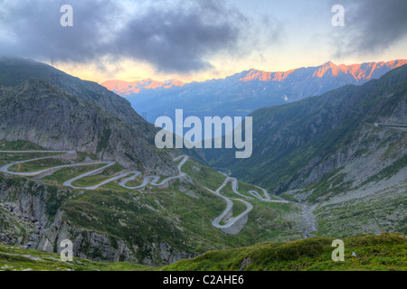 Old road with tight serpentines on the southern side of the St. Gotthard pass bridging swiss alps at sunset in Switzerland, Stock Photo