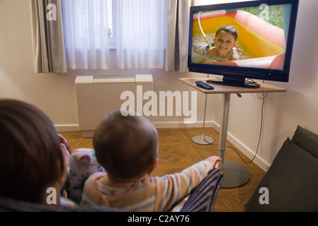 Siblings watching TV together Stock Photo