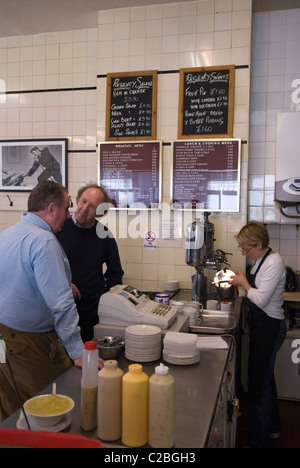 Lunchtime customers waiting to be served at Regency Cafe counter. Two men chatting, lady pouring a mug of tea. Westminster London SW1 UK. England   2011, 2010s HOMER SYKES Stock Photo