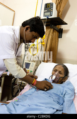 Doctor examining an elderly female patient with a stethoscope at Yashodhara Hospital, Sholapur, Maharashtra, India Stock Photo