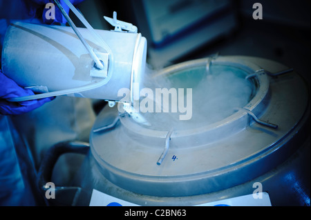 liquid nitrogen being poured from small container into large container blue Stock Photo