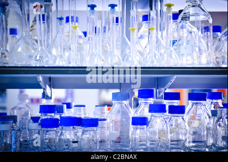 Glass bottles and jars beakers and test tubes with bright blue tops on shelf in science laboratory Stock Photo