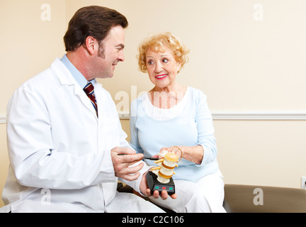 Chiropractor uses a model of the human spine to explain treatment to a new patient.  Stock Photo