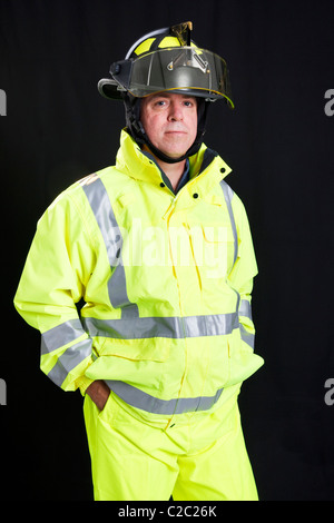 Handsome, rugged firefighter photographed on a black background. Stock Photo