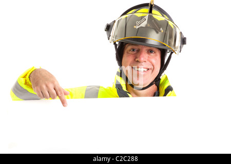 Friendly fireman in uniform, pointing to blank white space, ready for your message. Stock Photo