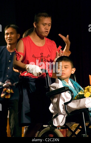 A young handicapped man is helping a disabled boy in a wheelchair at The Lao National Culture Hall in Vientiane, Laos. Stock Photo