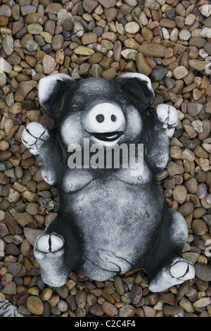 stone pig ornament on gravel bed Stock Photo