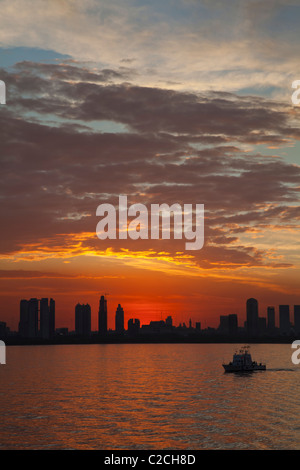 Tugboat and city skyline silhouetted at sunset, Buenos Aires Stock Photo