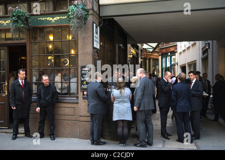 Woman in City of London. Lunchtime drinking culture. Leadenhall Market, group of businessmen office workers and one woman colleague having a lunch time drink together outside a city pub. London England  EC3 UK. 2010s HOMER SYKES Stock Photo